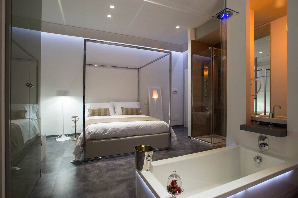 Une chambre moderne dotée d’un grand lit, d’une douche à parois de verre et d’une salle de bain séparée avec une baignoire.