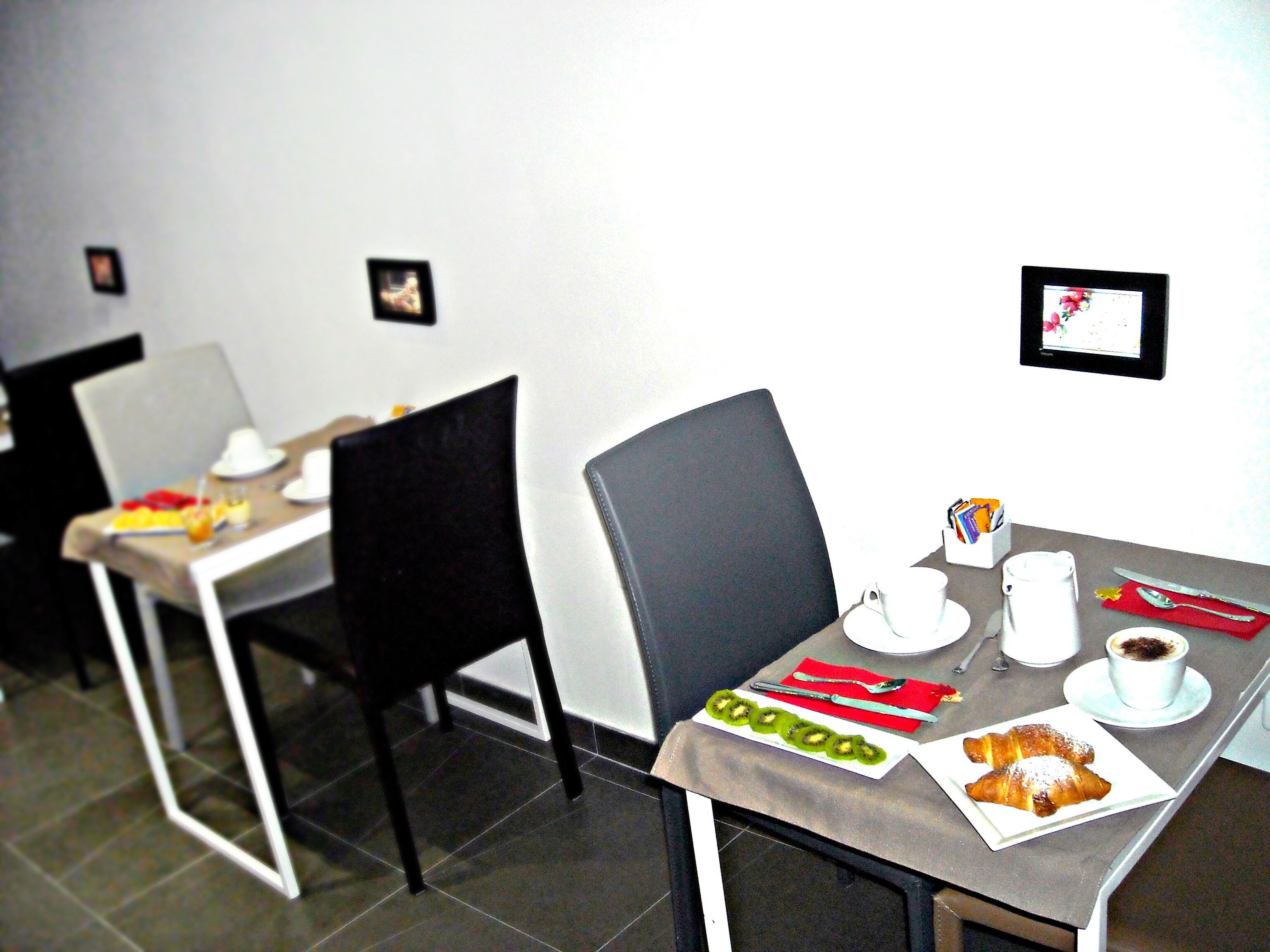 A dining area with tables set for breakfast, including croissants and a cup of coffee.