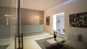 A modern interior with a glass wall displaying welcome messages, a vase with flowers on a table, and artwork on the walls. - Hotel Santa Brigida (Naples)
