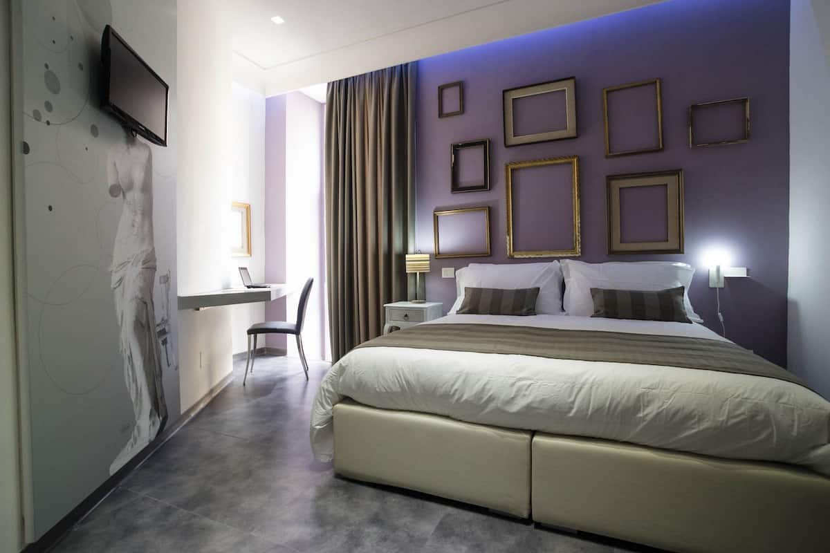 Une chambre d’hôtel moderne, dotée d’un grand lit, d’un bureau et d’un téléviseur fixé au mur.