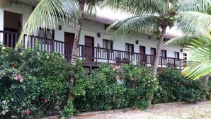 Hotel amb teulada de palla, balcons de fusta i vegetació abundant.