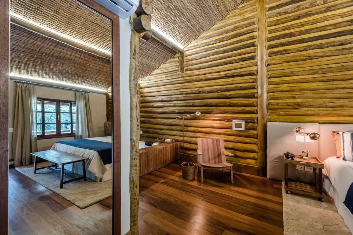 Una habitación tipo cabaña de madera con una cama, una silla, un escritorio y una ventana.