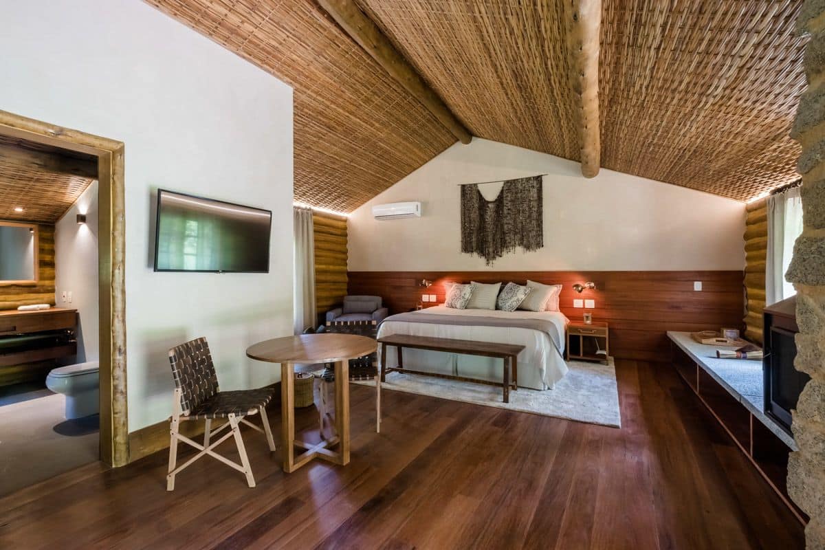 Un dormitorio acogedor con techo de madera, una cama, un televisor y una pequeña mesa con una silla.