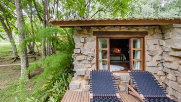 A stone building with a wooden deck, two sun loungers, and a door leading inside.