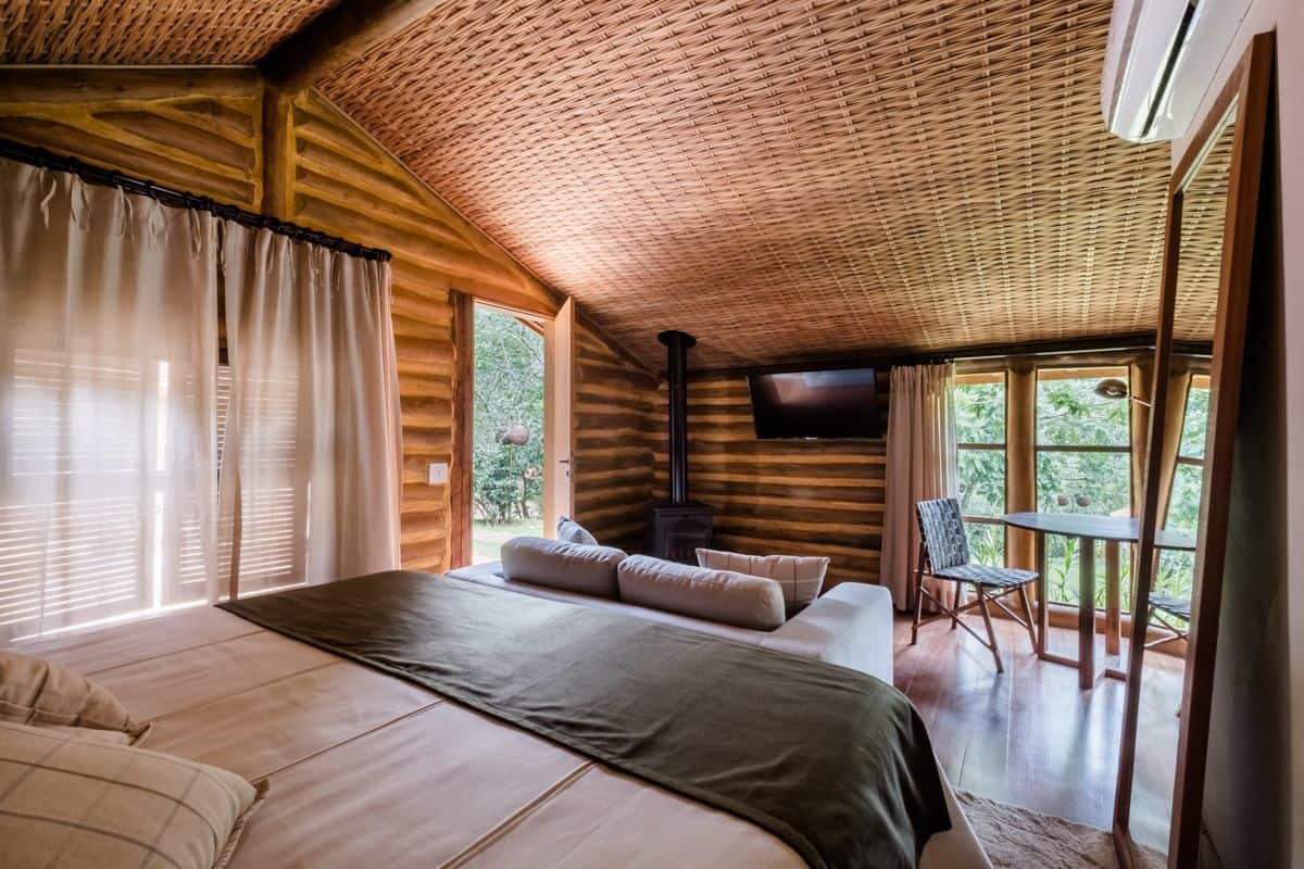 Un dormitorio con una cama grande, televisor, chimenea y vistas al exterior.