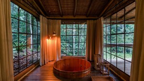A wooden room with a large window, a wooden bathtub, and a small wooden table. - Pousada Tankamana (Petrópolis)