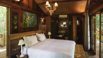 A wooden room with a large bed, a chandelier, and artwork on the walls.