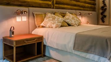 Quarto com cabeceira de madeira, mesa de cabeceira, abajur e cama com almofadas estampadas.