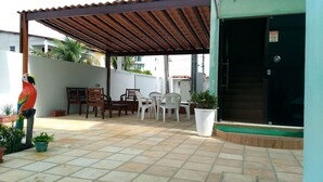 A covered patio with outdoor furniture, a bird sculpture, and potted plants. - Pousada Porto de Galinhas (Ipojuca)