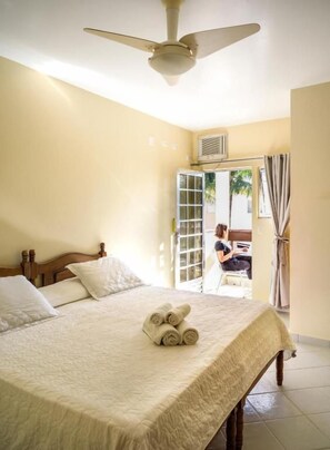 Un dormitorio con una cama, ventilador de techo y vistas al exterior.