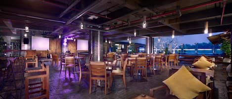 A restaurant with wooden tables and chairs, a bar area, and a view of the outdoors.