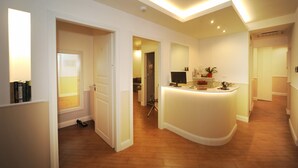 A hotel lobby with a reception desk, a staircase, and a hallway leading to other rooms. - My Suites Piazza di Spagna (Rome)