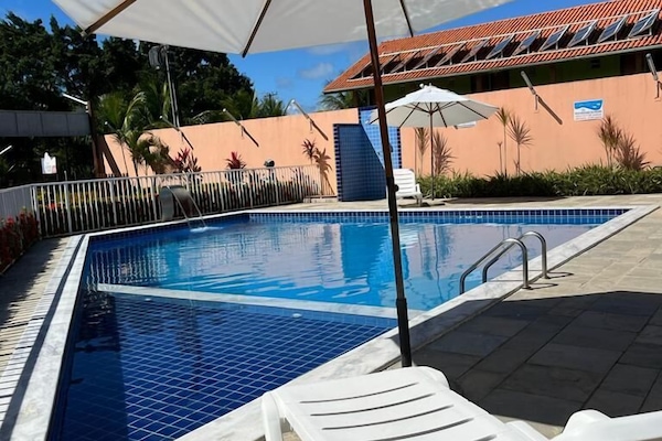 Una piscina al aire libre, sombrillas, tumbonas