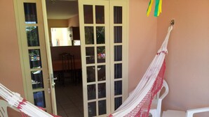 A hammock in a room with a tiled floor and white plastic chairs. - Recanto Sonhos do Porto (Ipojuca)