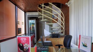 A modern office space with a spiral staircase, a glass desk, and a Kibon ice cream display. - Recanto Sonhos do Porto (Ipojuca)