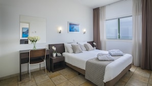 Een hotelkamer met een bed, bureau, stoel en een raam met gordijnen.