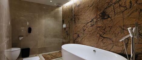 Un baño moderno con una bañera independiente, una ducha con cerramiento de vidrio y una pared de mármol.