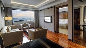 Een moderne hotelkamer met een groot raam, een flatscreen televisie, een bank, een bijzettafeltje en een bed.