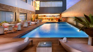 Een modern hotel met een zwembad, terras en een goed verlicht interieur.
