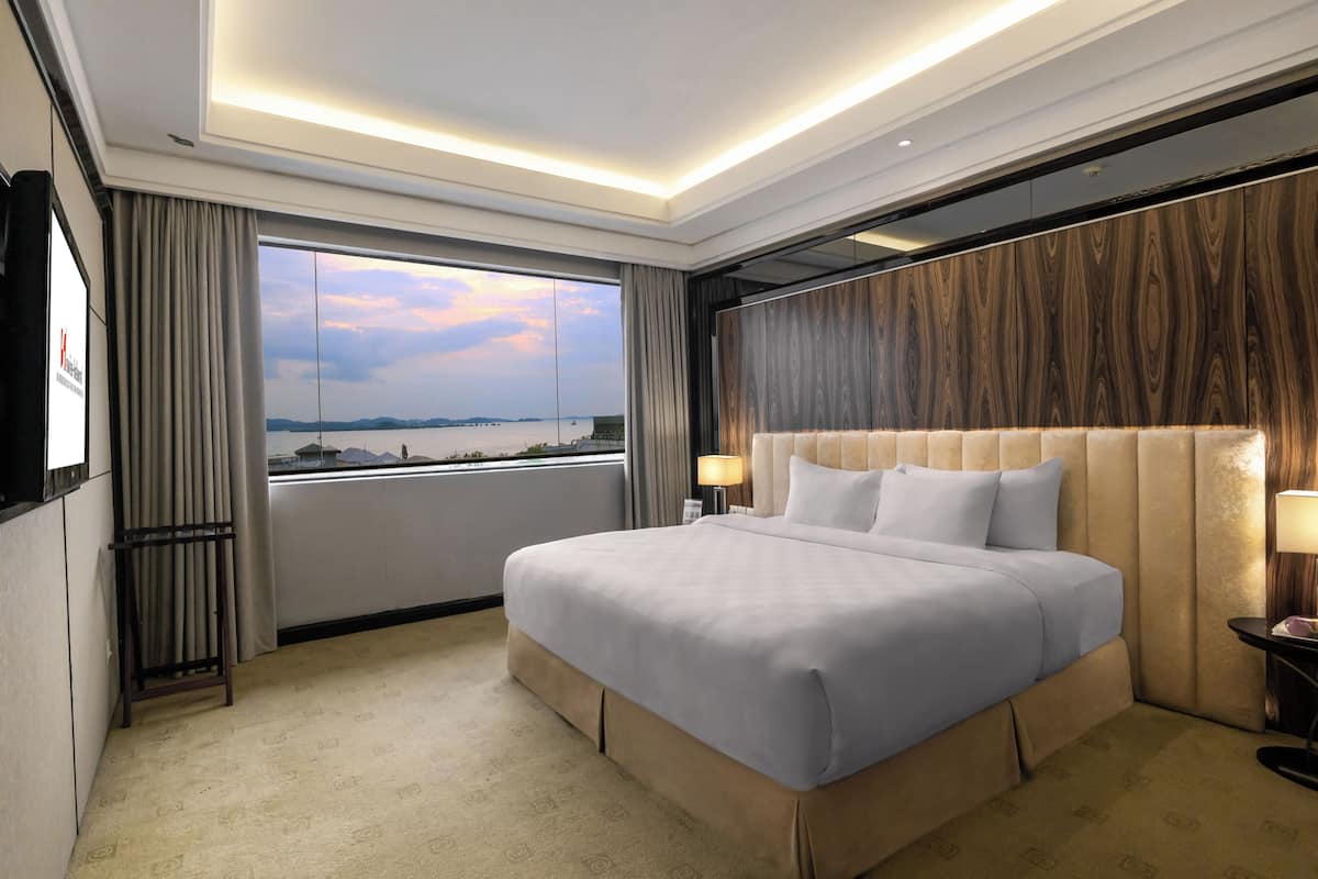 Een moderne hotelkamer met een groot bed, uitzicht op zee en een wand van hout.