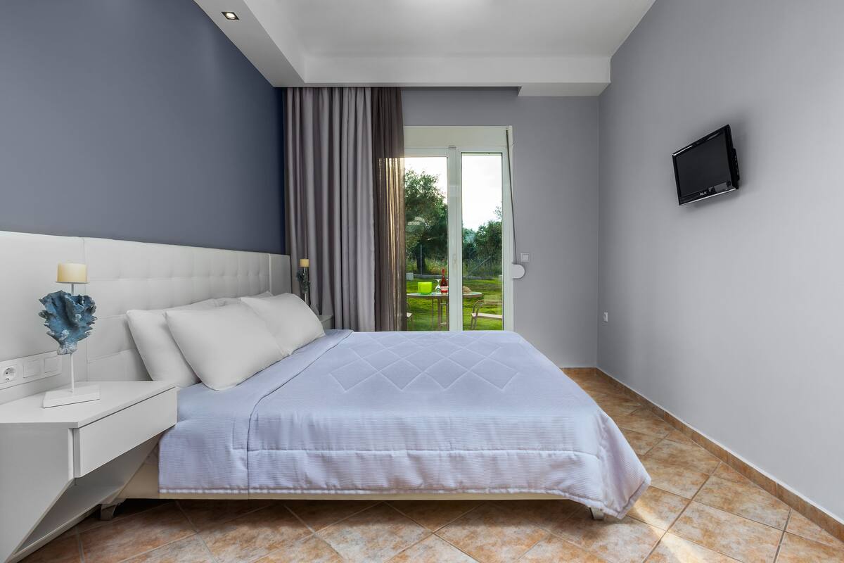 Una camera da letto moderna con un letto, un comodino e una TV a parete.