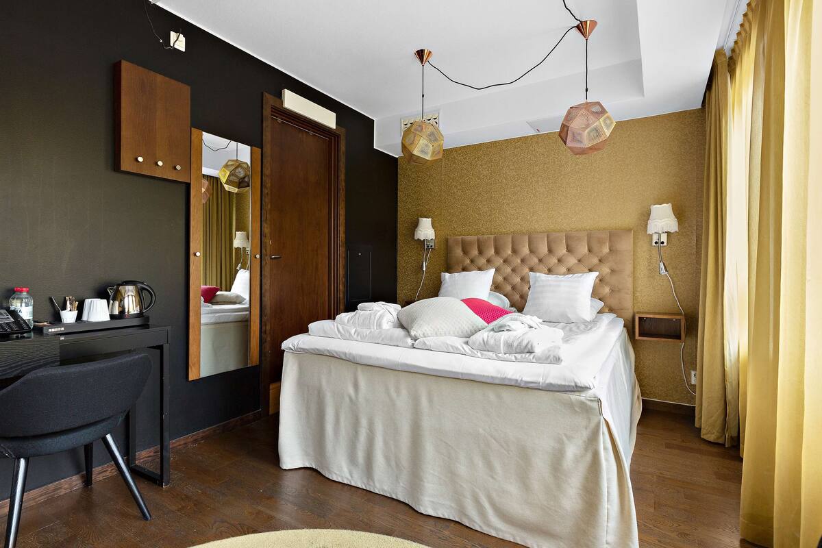 A modern hotel room with a large bed, a desk, and a chair.
