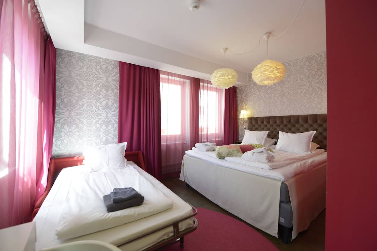 A hotel room with two beds, a red carpet, and a patterned wallpaper.