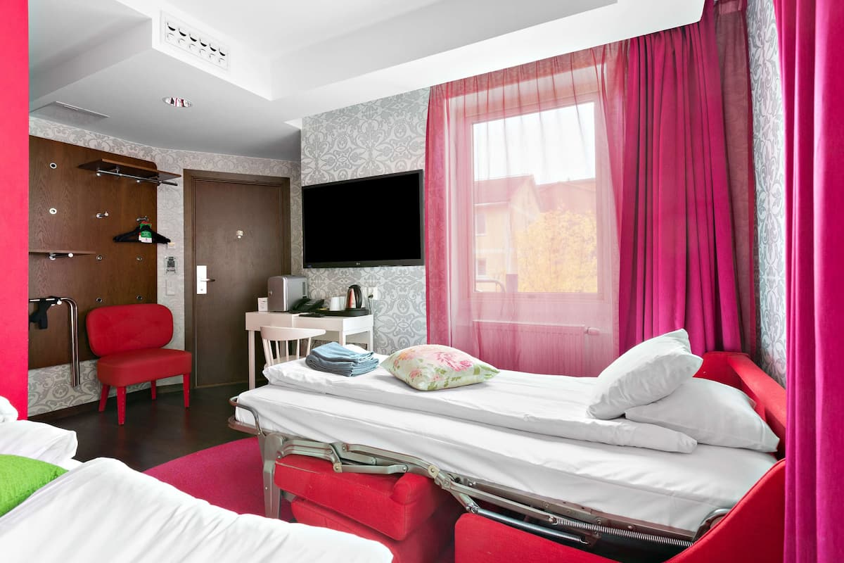 A hotel room with a bed, a desk, a chair, and a television.