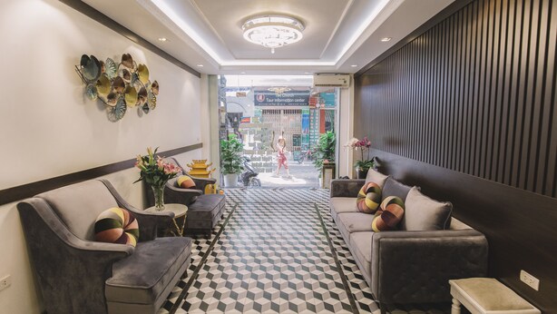 A modern lobby with a checkered floor, grey sofas, and a decorative wall piece.