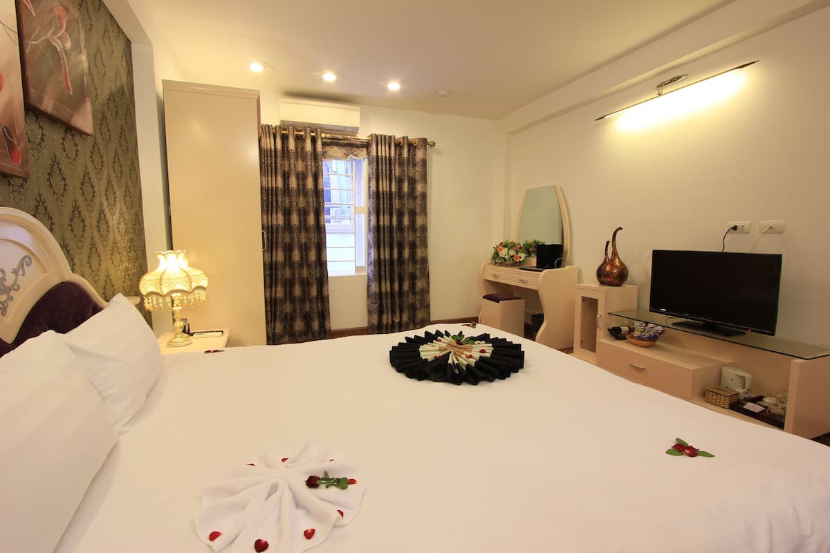 A hotel room with a bed, a desk, a television, and a window with curtains.