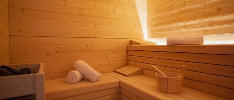 Una sauna de madera con bancos, una toalla y un cubo.