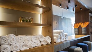A hotel reception area with wooden shelves displaying rolled towels and a mirror reflecting the space. - Villa Imperina (Agordo)