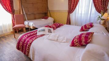 A hotel room with two beds, a wooden headboard, a chair, and a window with curtains.