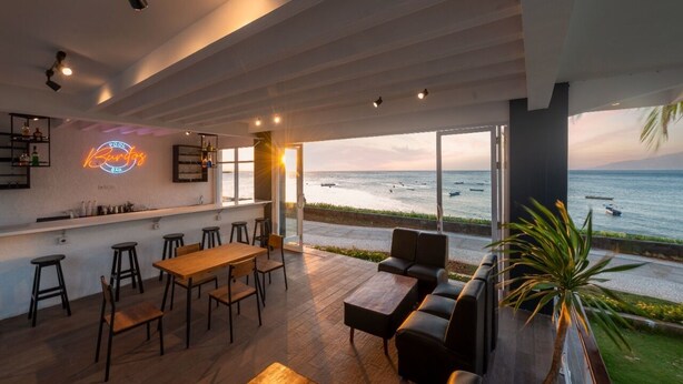 Un bar moderne avec un panneau lumineux au néon, des meubles en bois et une vue sur la mer.