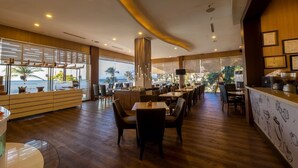 Un restaurant doté d’un plancher, de tables et de chaises en bois, et offrant une vue sur l’océan.