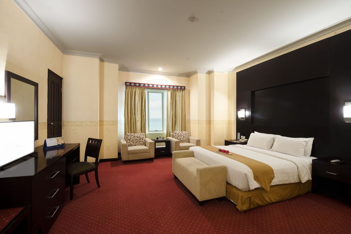 Ein Hotelzimmer mit einem Bett, zwei Sesseln, einem Schreibtisch und einem Fernseher.
