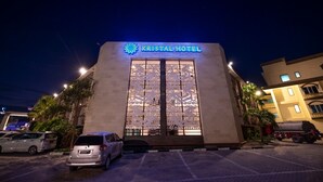 Un hôtel appelé «KRISTAL HOTEL», doté d’une façade moderne, de grandes fenêtres et d’un parking où sont garées des voitures.
