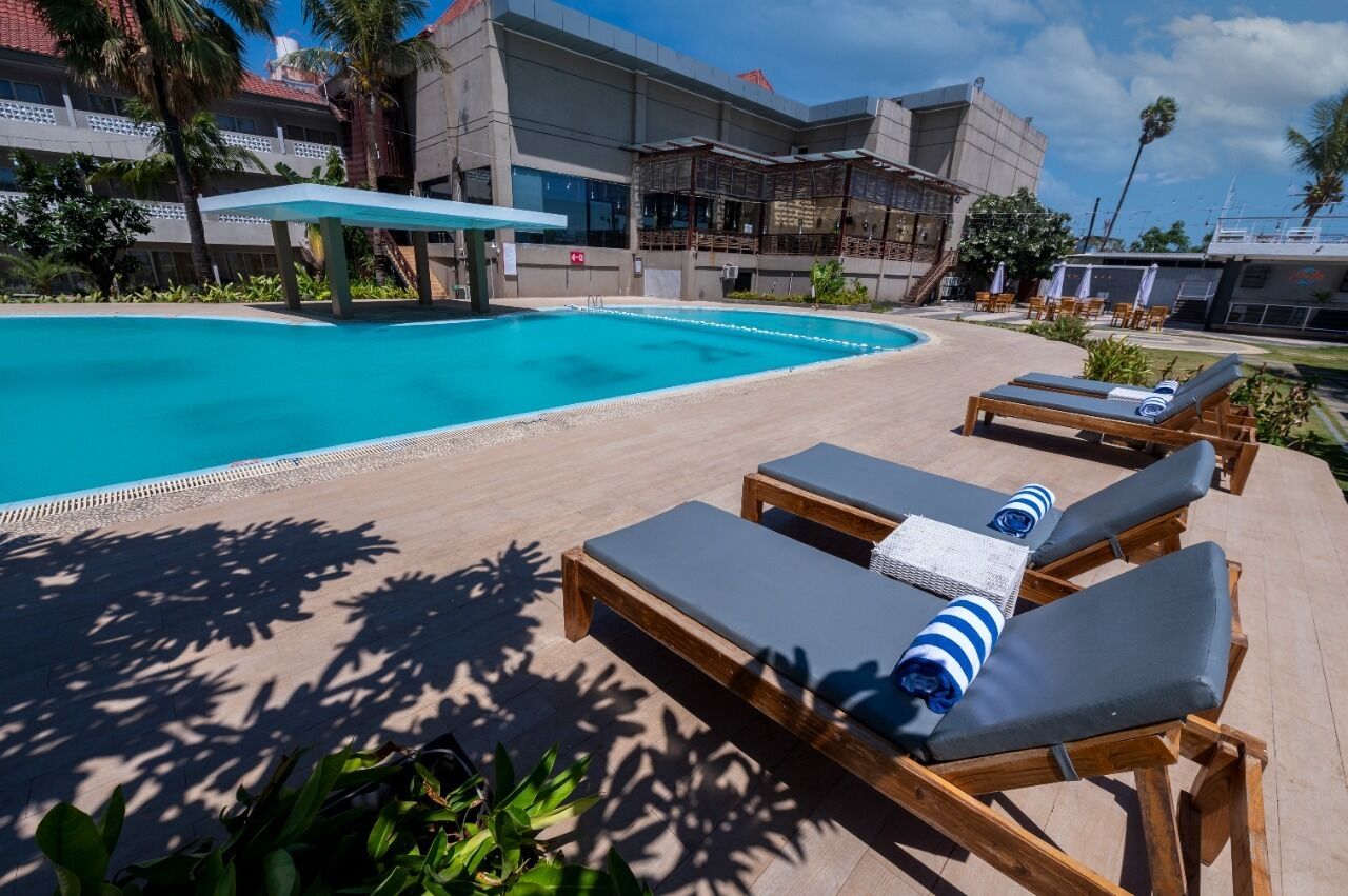 Un espace piscine avec des chaises longues et un coin salon abrité.