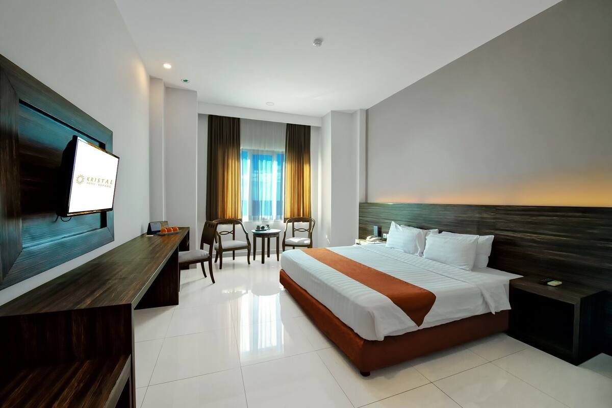Ein Hotelzimmer mit Bett, Schreibtisch, Fernseher und Meerblick.