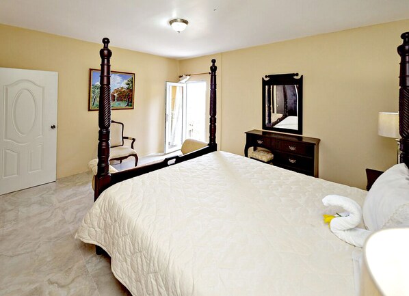 A four-poster bed with a white bedspread, a dresser with a mirror, and a chair in a room with beige walls and a white door. - Starlight Chalet (Silver Hill Gap)