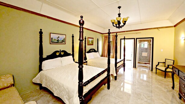 A four-poster bed with a white bedspread, a wooden dresser, and a chair in a well-lit room with a marble floor. - Starlight Chalet (Silver Hill Gap)