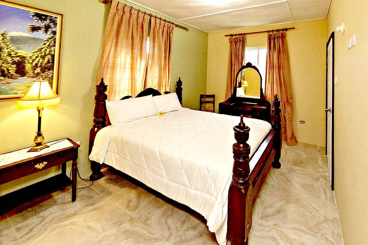 Un dormitorio con una cama grande, una mesita de noche, un aparador, un espejo y un cuadro en la pared.
