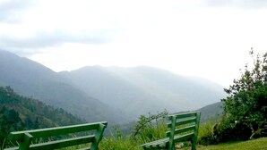 Two green benches on a grassy hill with a view of mist-covered mountains in the background. - Starlight Chalet (Silver Hill Gap)