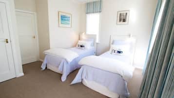 Een slaapkamer met twee bedden, een raam met gordijnen en een deur.