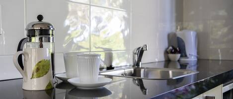 A kitchen with a coffee maker, a cup, and a sink.