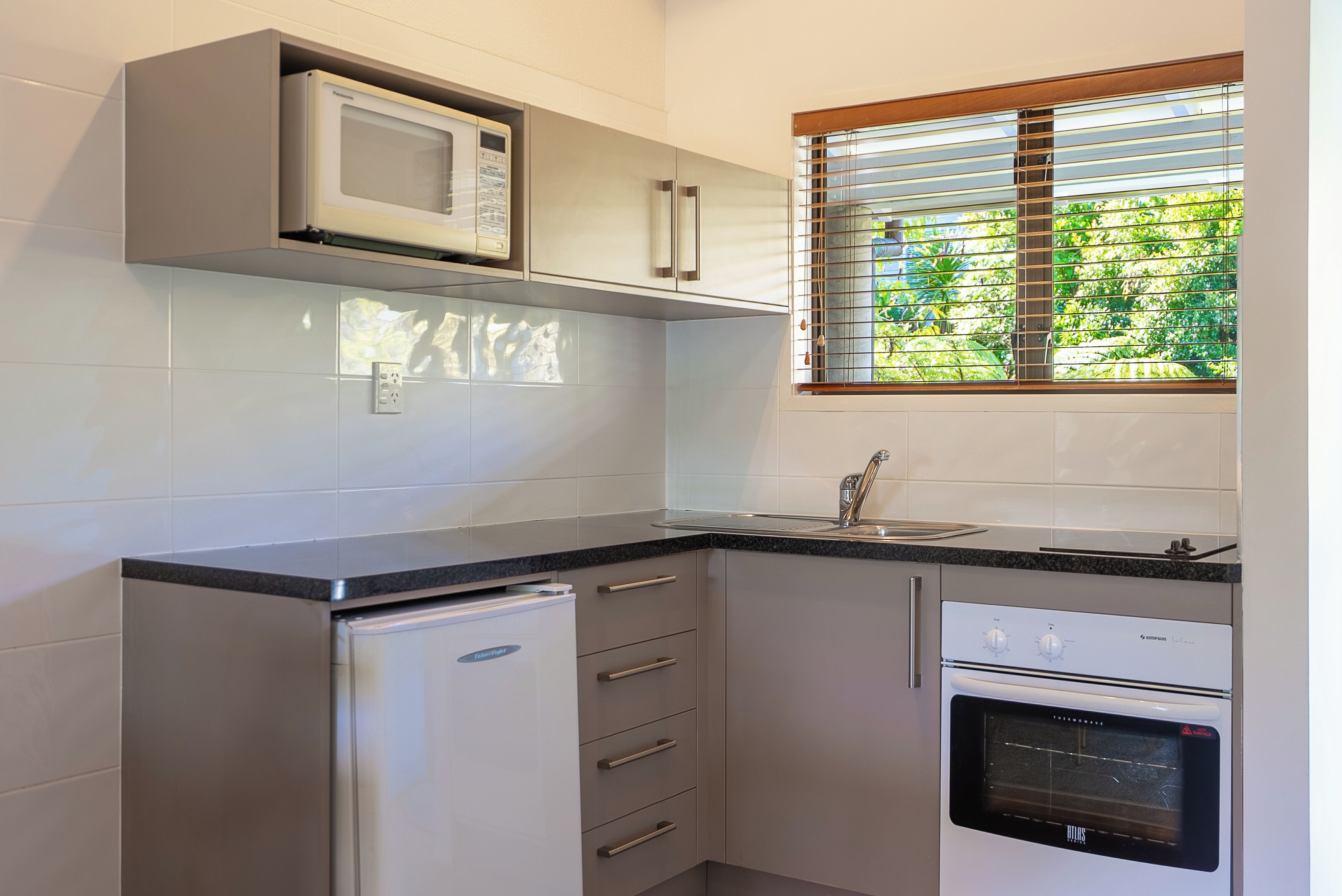 Una cocina compacta con microondas, horno y refrigerador integrados.