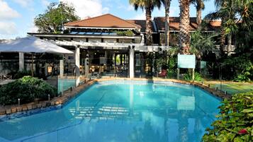Relax by the resort's pool surrounded by lush greenery and lounge chairs.