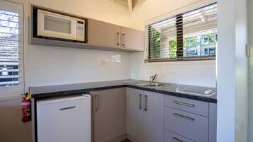 A compact kitchen with a microwave, sink, and a small refrigerator.