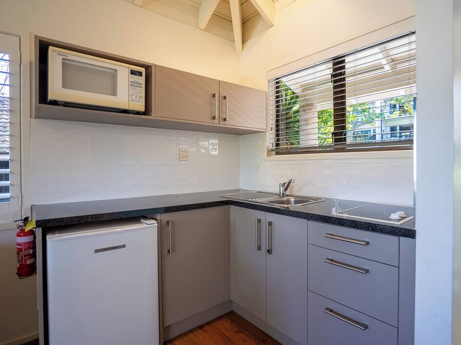 A compact kitchen with a microwave, sink, and a small refrigerator.