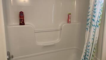 A bathroom with a bathtub, a shower curtain, and two bottles of soap on the wall.